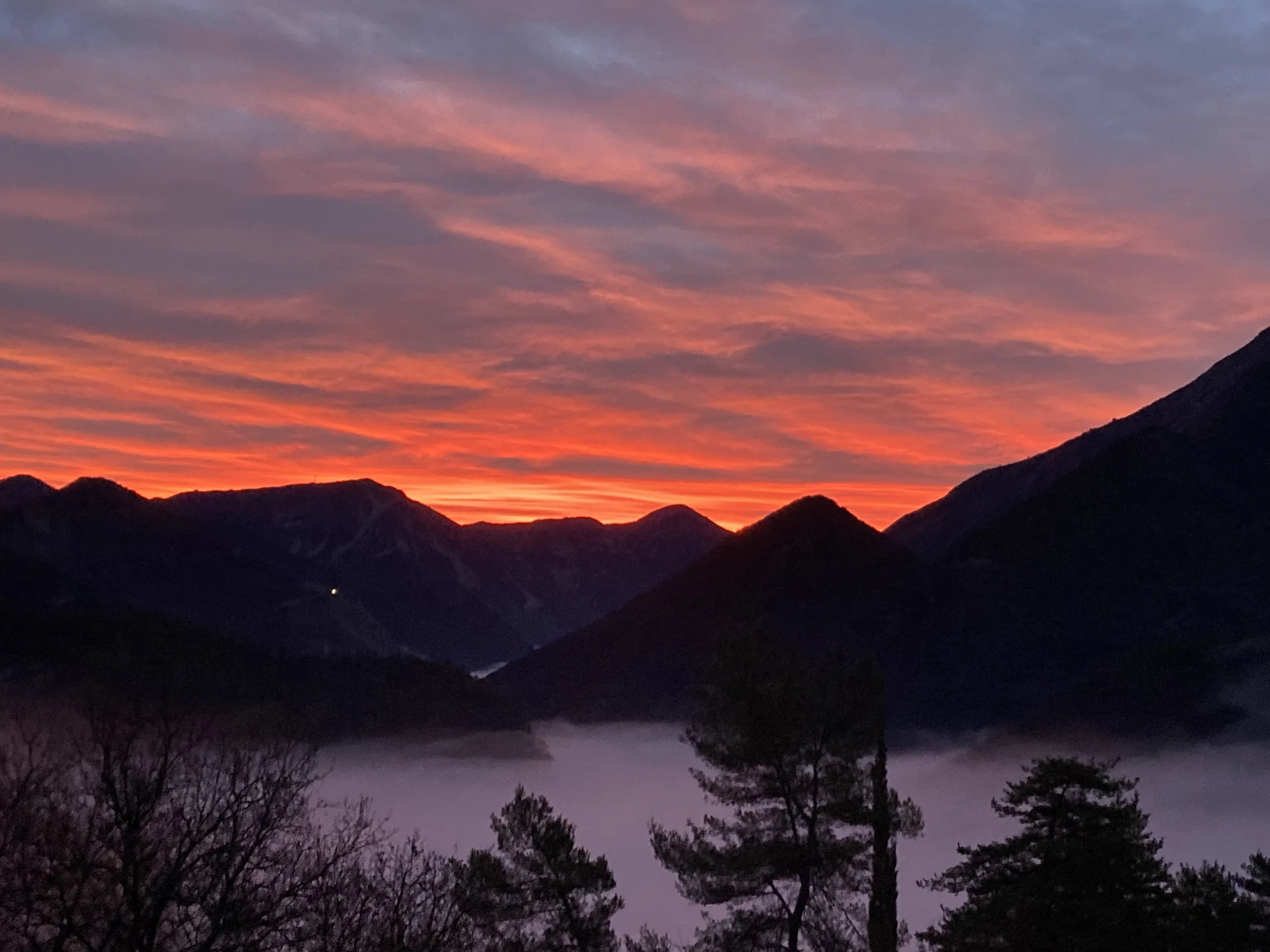 Coucher de soleil spectaculaire vu depuis la Villa Charlène, avec des teintes dorées sur les montagnes.