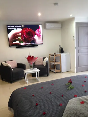 Suite Marilyne avec lit king size, chaise massante et décoration chaleureuse pour une escapade intime.