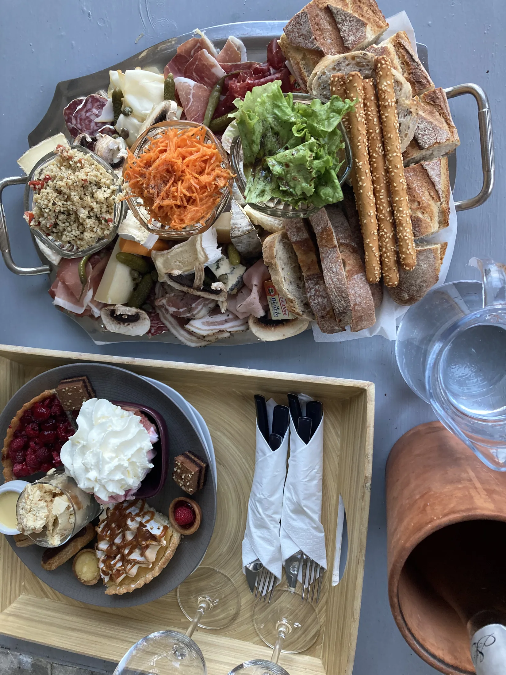 Plateau repas gourmet avec sélection de charcuterie fine et bouteille de vin, servi en chambre.